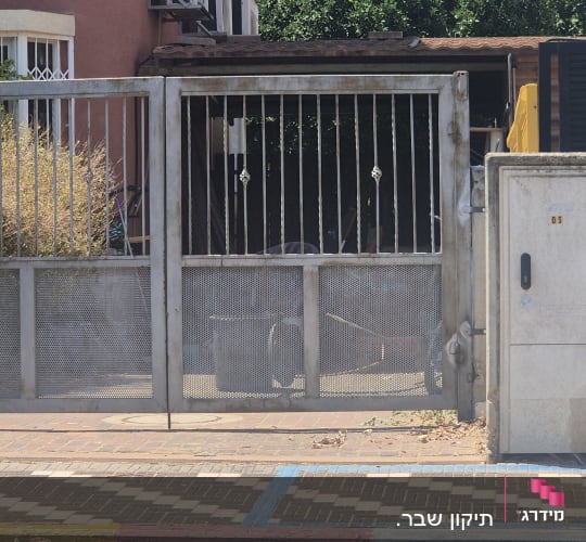 שער מתכת ליד בית עם צמחייה